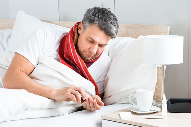 Man in bed taking pills